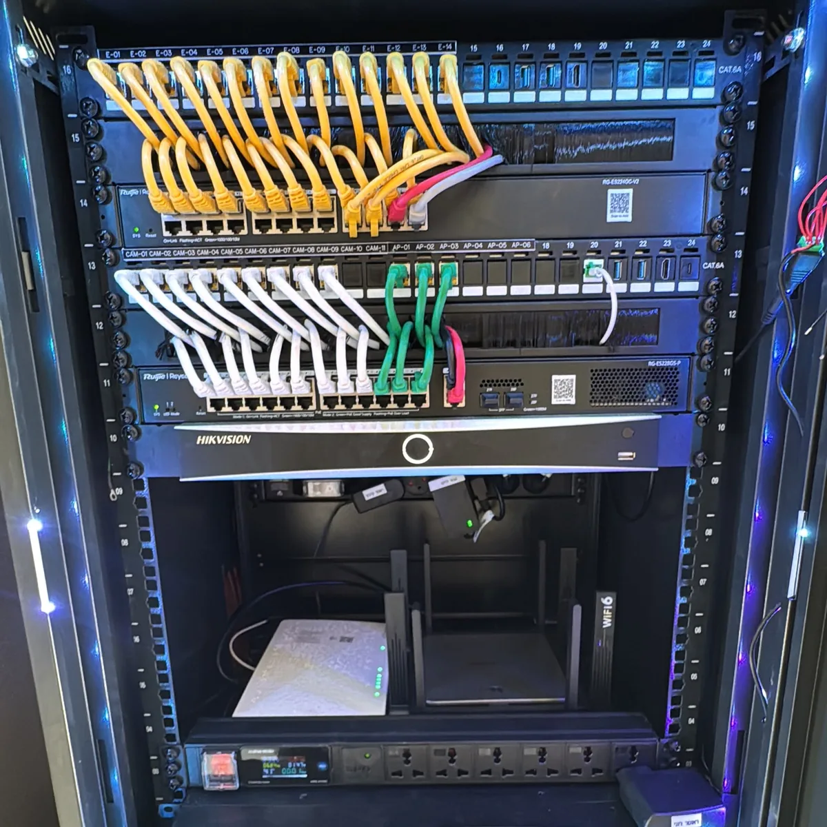 ארון תקשורת עסקי מסודר של YR.Fiber עם פאנלים מסומנים, כבלי פאטץ' צהובים ולבנים, מתגי Ruijie ומקליט Hikvision